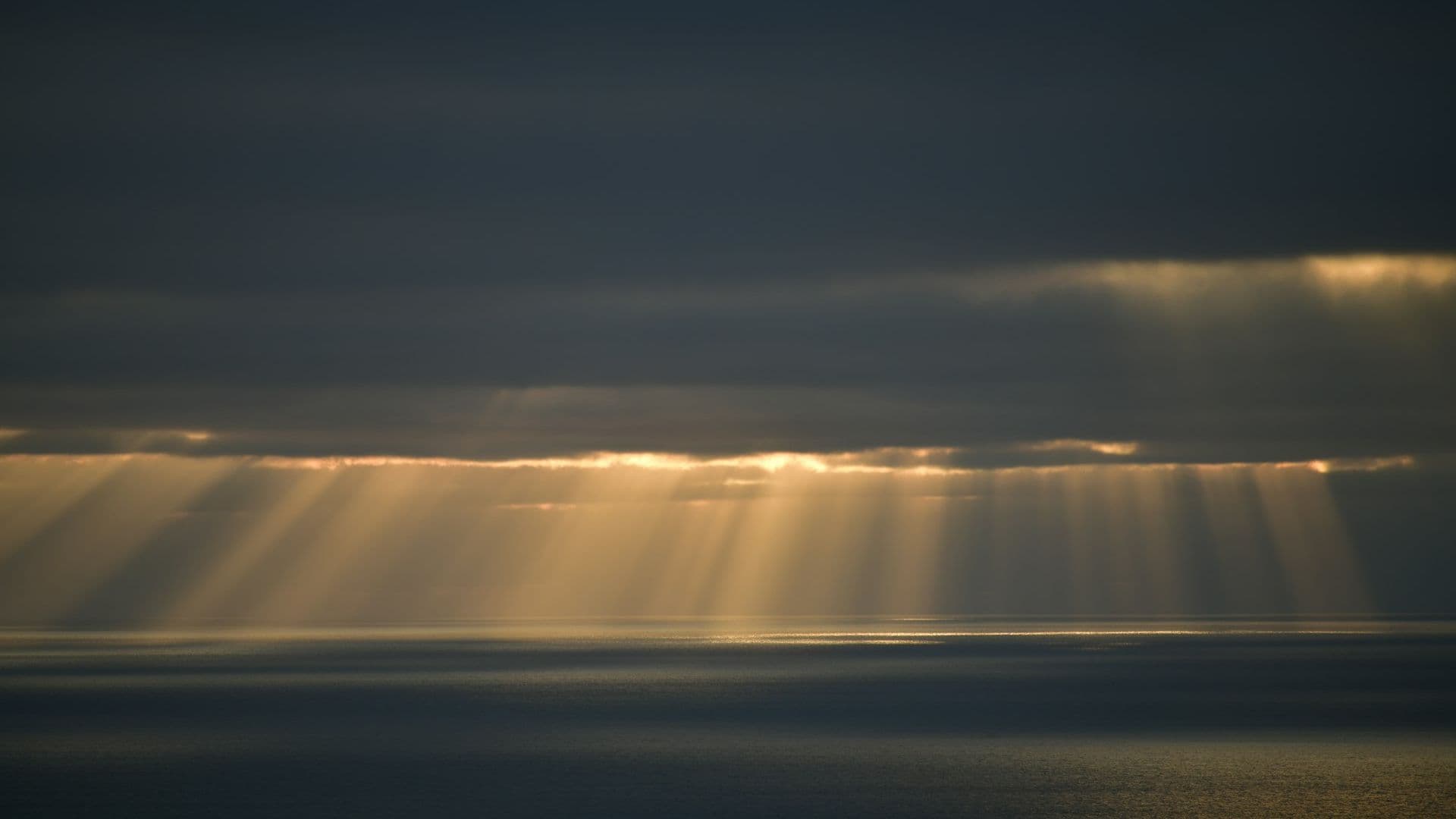 Sunlight streaming through dark clouds over the ocean